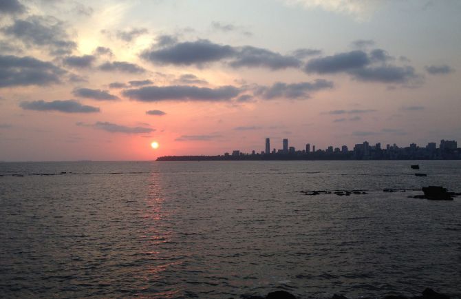The sky turns a pinkish hue as the sun sets over Mumbai's Marine Drive.